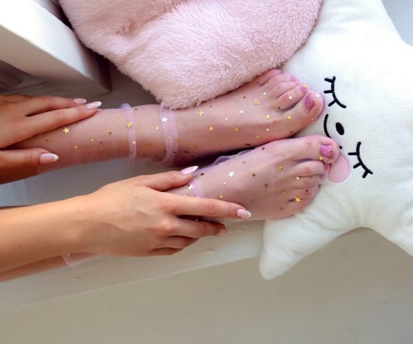 Beautiful groomed woman's feet in the socks with stars. Care about nails and clean, soft, smooth body skin. Pedicure and manicure beauty salon.